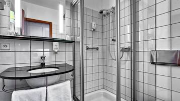A modern bathroom with a glass-enclosed shower, a black countertop sink, and a white toilet.