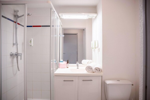 A bathroom with a shower, toilet, and sink.