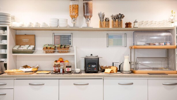 A kitchen area with a bread machine, jars of jam, and a coffee maker. - Comfort Aparthotel Besancon La City (Besancon)