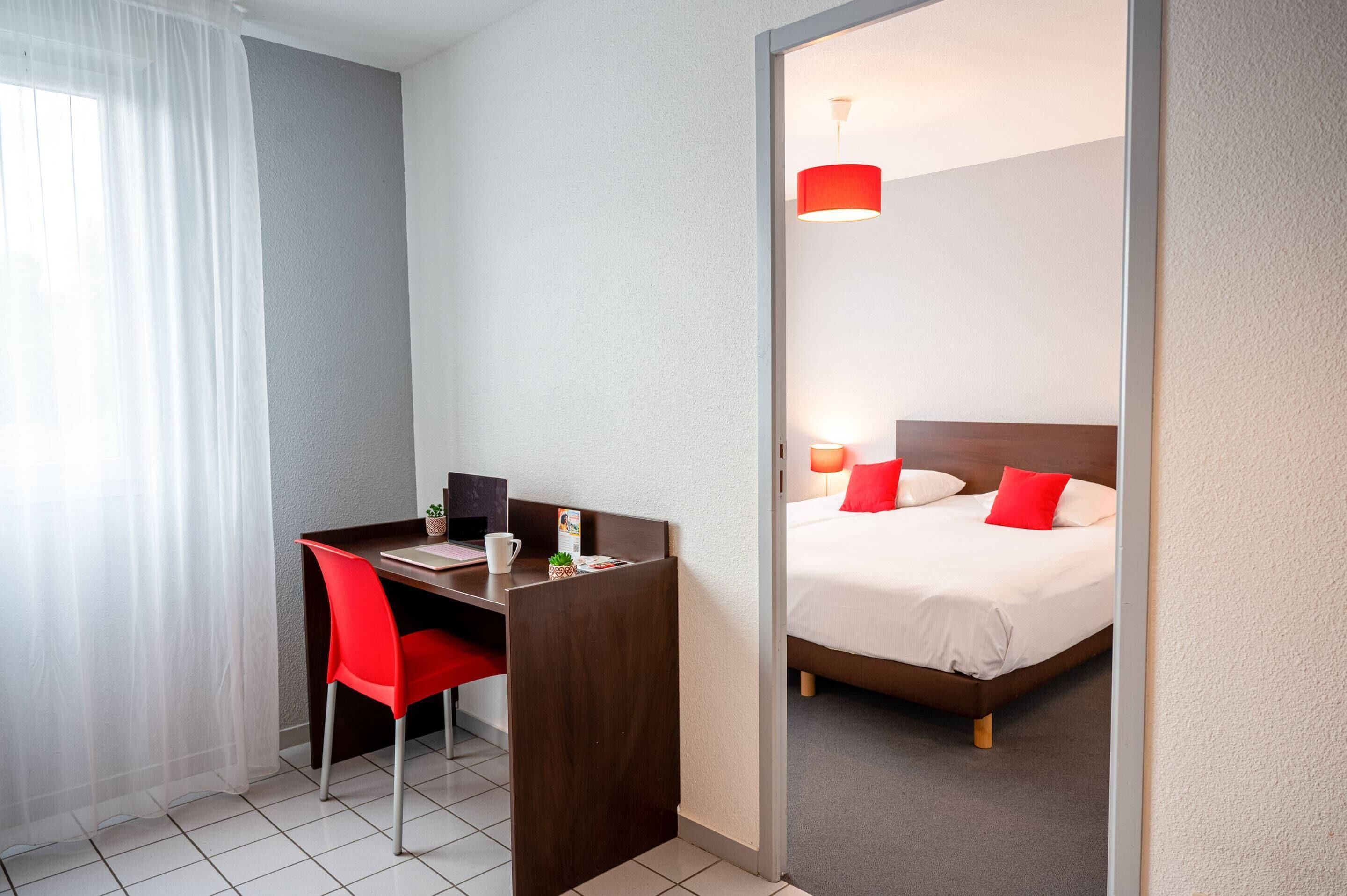 Ein Hotelzimmer mit Schreibtisch, Stuhl und Bett.