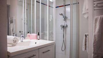 A bathroom with a glass-enclosed shower, a white sink, and a mirror.
