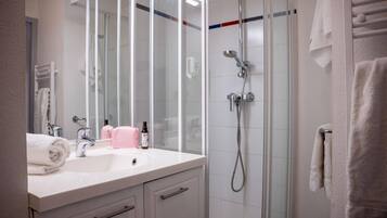 A modern bathroom with a glass shower enclosure, a white sink with a mirror, and a towel rack.