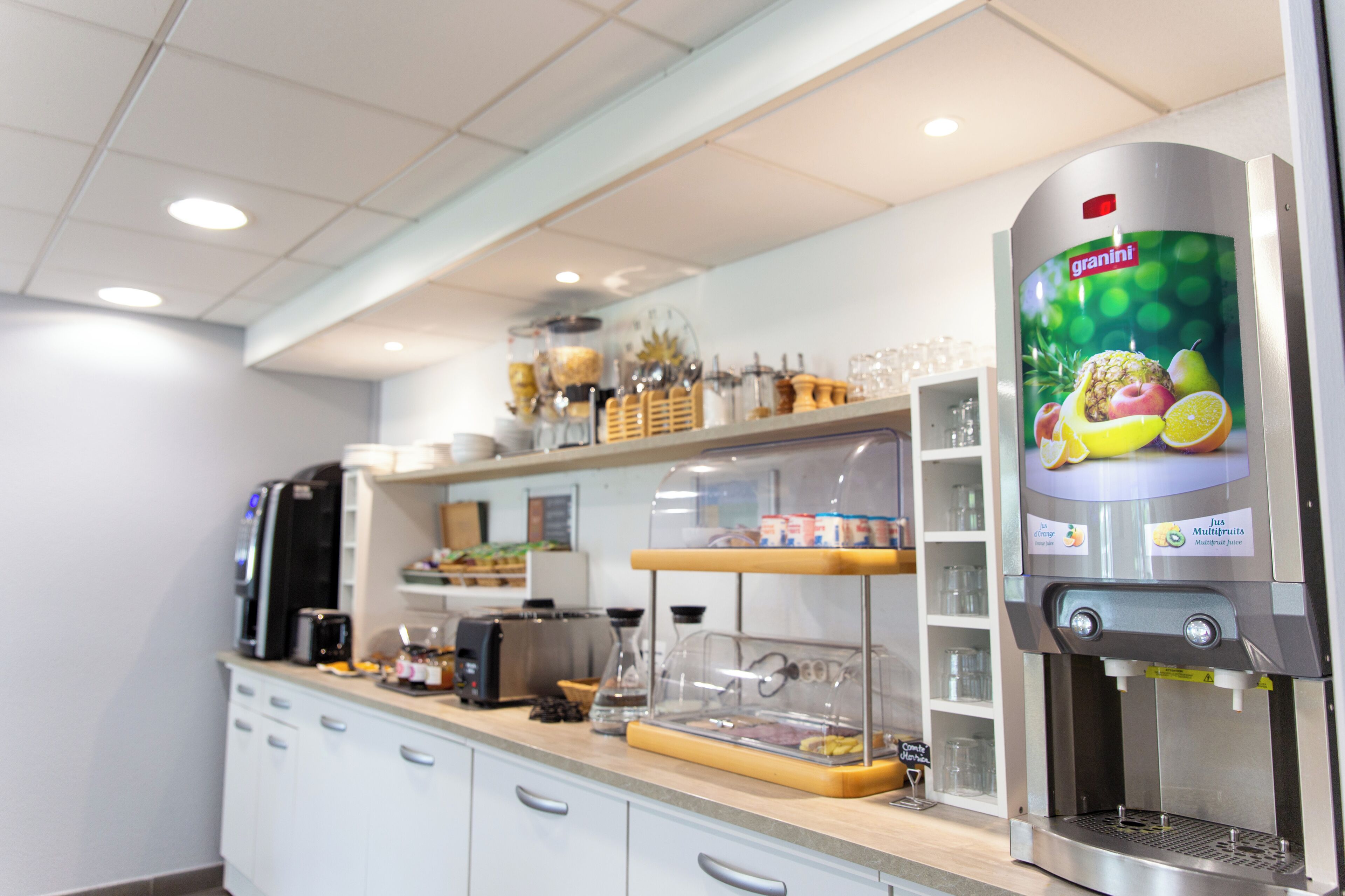 Ett modernt köksområde med en juiceautomat från Granini, en kaffemaskin och diverse köksredskap.