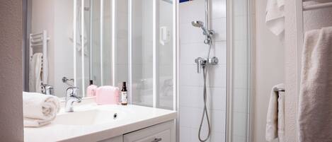 A modern bathroom with a glass shower enclosure, a white sink, and a mirror.