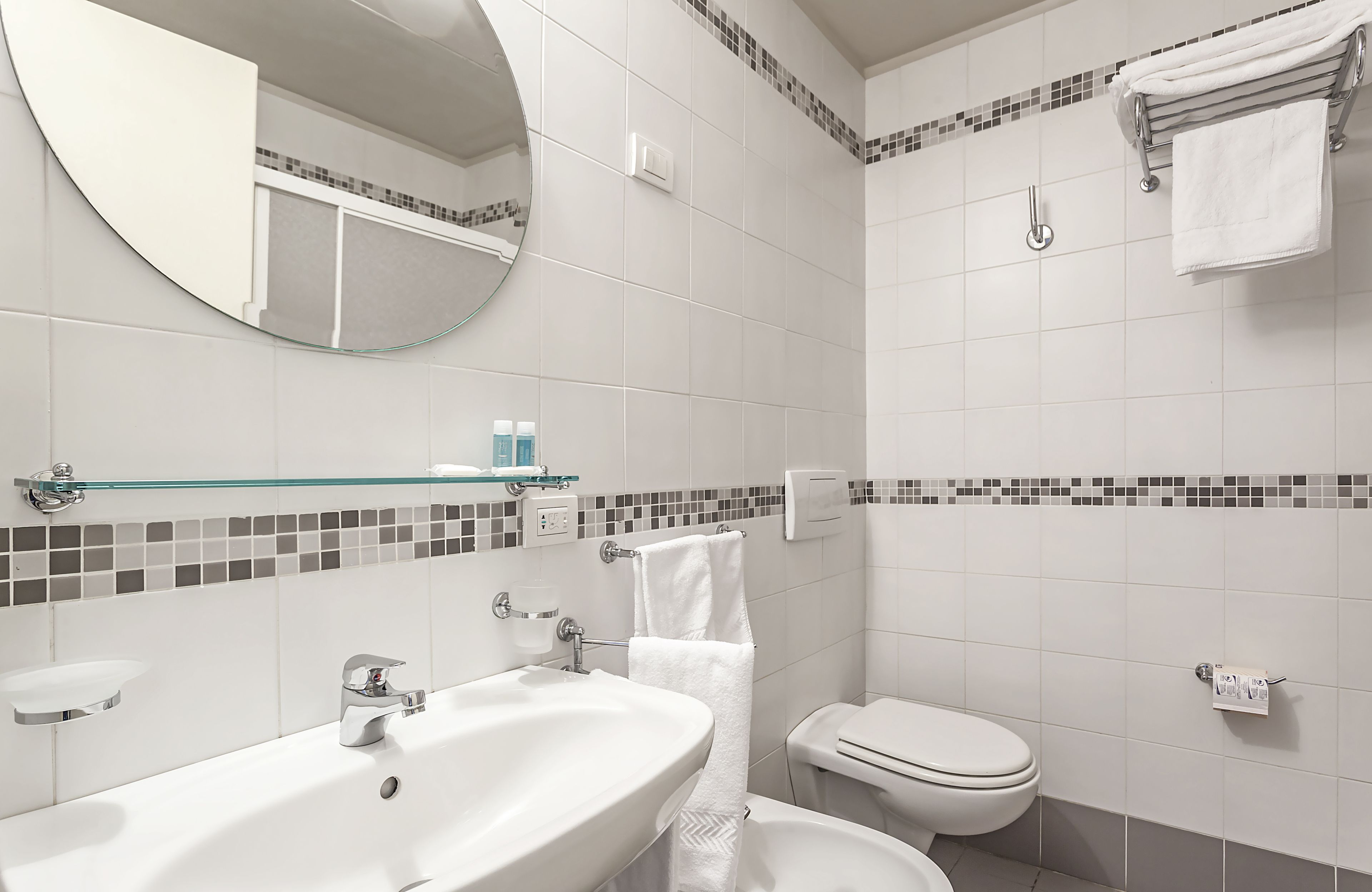 Een moderne badkamer met een grote wastafel, spiegel, toilet en douche.