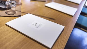 A wooden table with a menu, a glass, and a booklet.