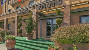 The exterior of the Grand Hotel Bonanno with steps leading to the entrance, large potted plants, and a clear view of the entrance doors. - Grand Hotel Bonanno (Pisa)