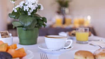 Ein Frühstückstisch mit einer Tasse Kaffee, einer Fruchtplatte, Gebäck und einem Glas Orangensaft.