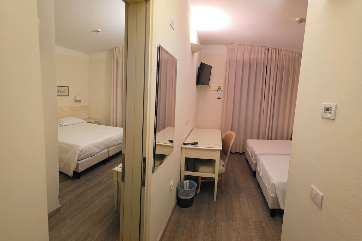 A hotel room with a bed, a desk, a chair, a television, and a curtain.