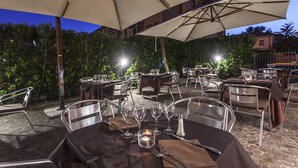 An outdoor dining area with tables and chairs, umbrellas, and candles. - Grand Hotel Bonanno (Pisa)