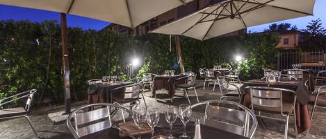 An outdoor dining area with tables and chairs, umbrellas, and candles.