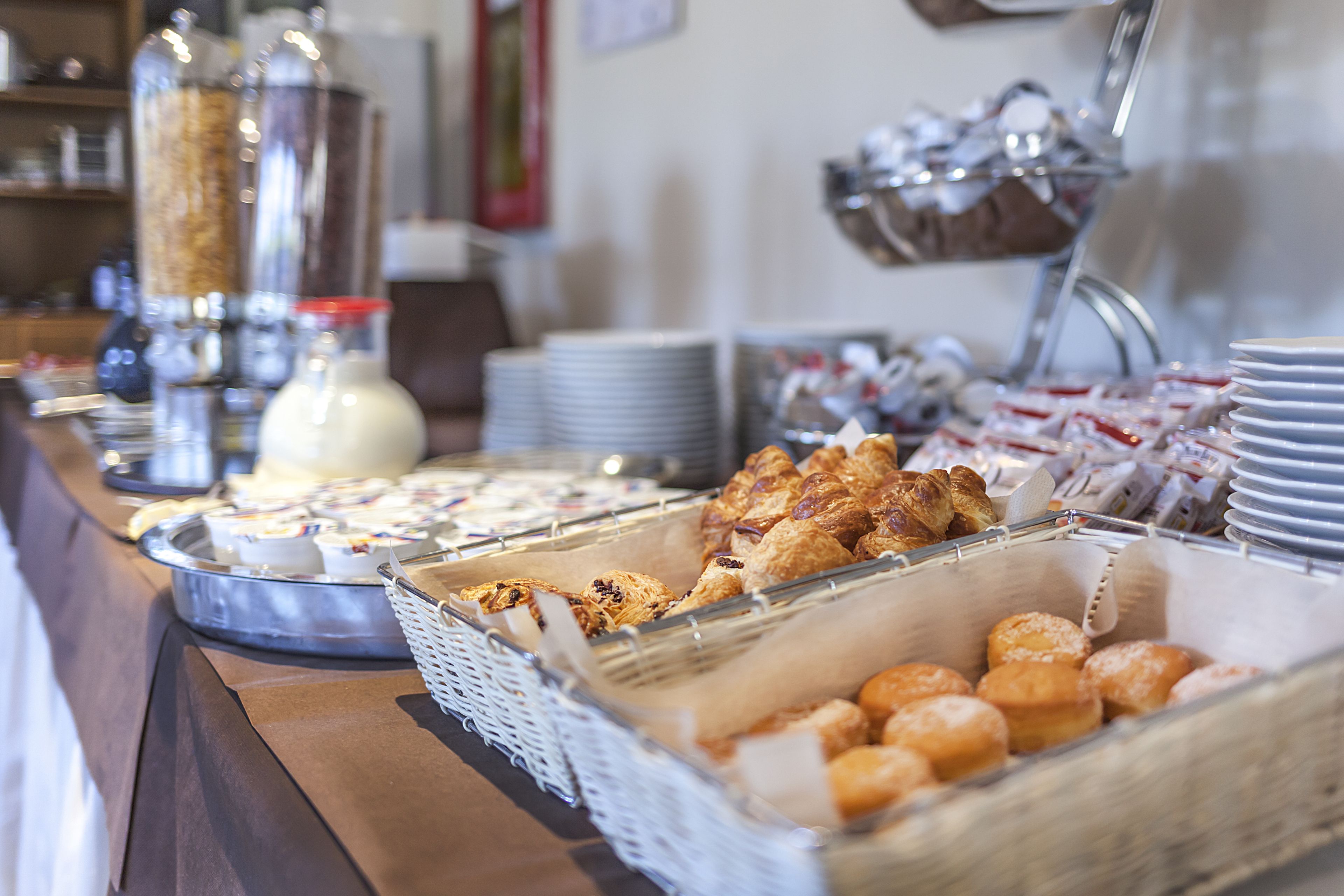A buffet with various food items, including pastries and bread, arranged on a counter.
