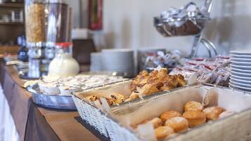 Un buffet proposant une variété de plats, notamment des pâtisseries et du pain, disposés sur un comptoir.