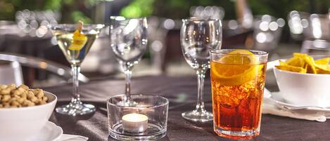 A table set with various glasses, a candle, and a bowl of nuts.