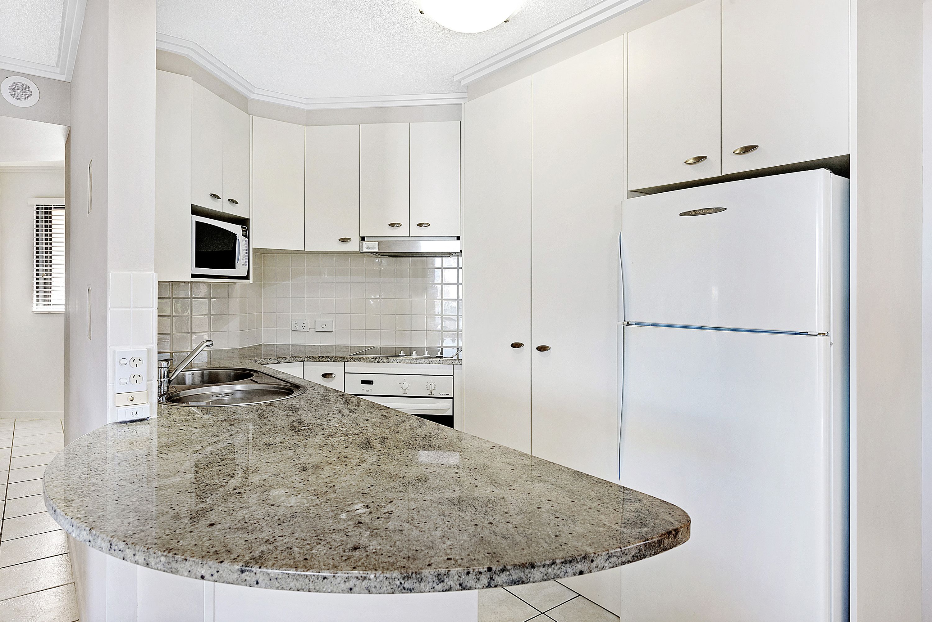 A kitchen with white cabinets, a granite countertop, stainless steel appliances, and a tiled backsplash.