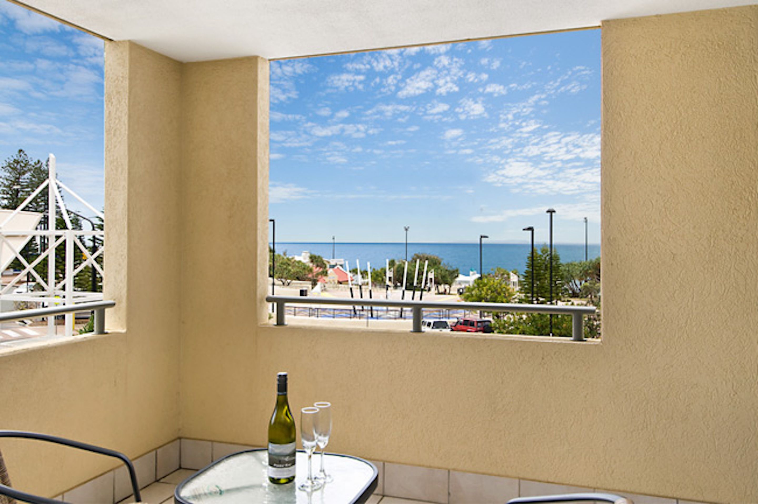 A balcony with a table, a bottle, and two glasses.
