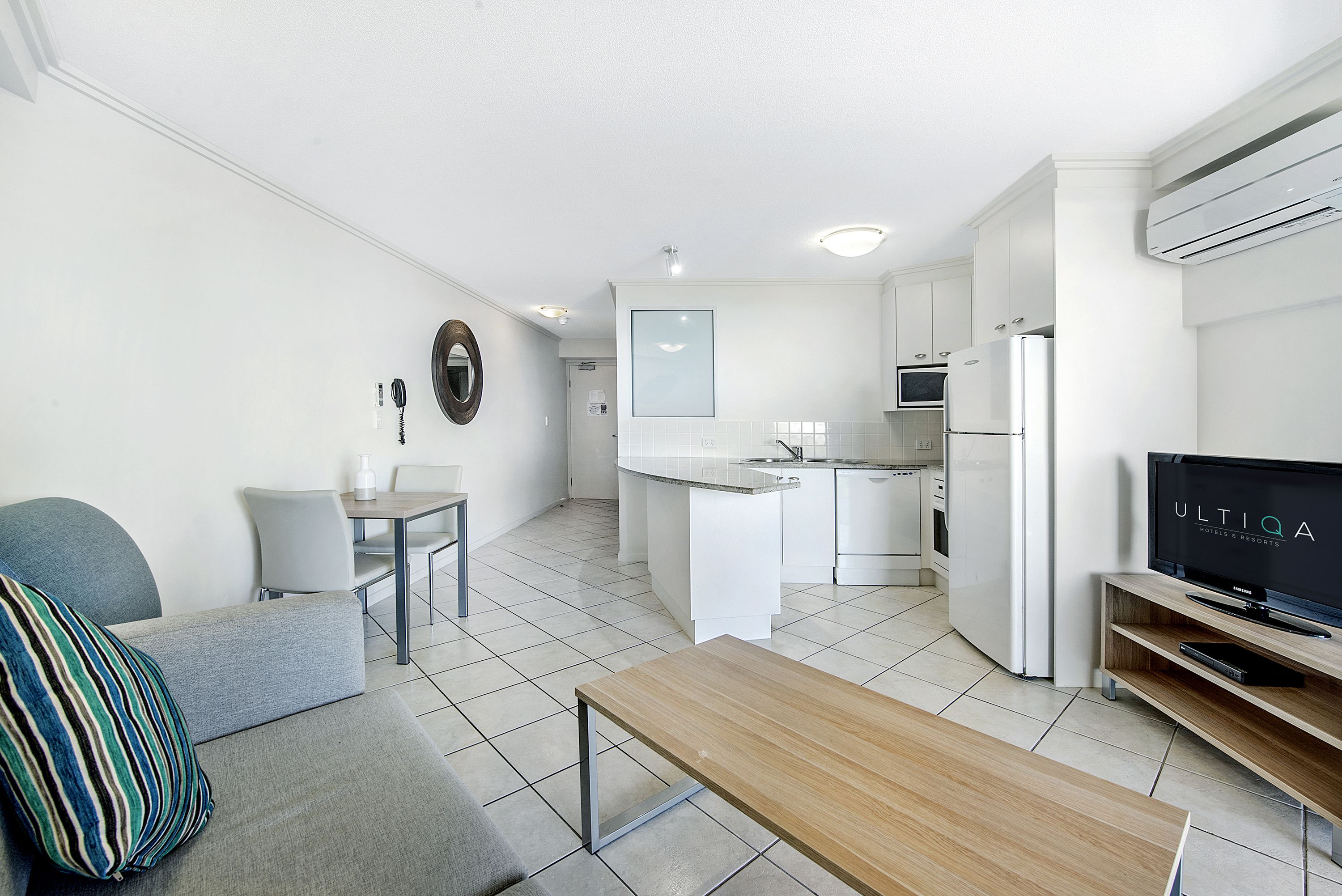 Een moderne, compacte woonruimte met een kitchenette, een eethoek en een zithoek met een televisie.