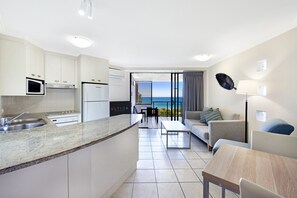 Een moderne keuken met een groot eiland, een eethoek met uitzicht en een zithoek met een bank en een lamp.