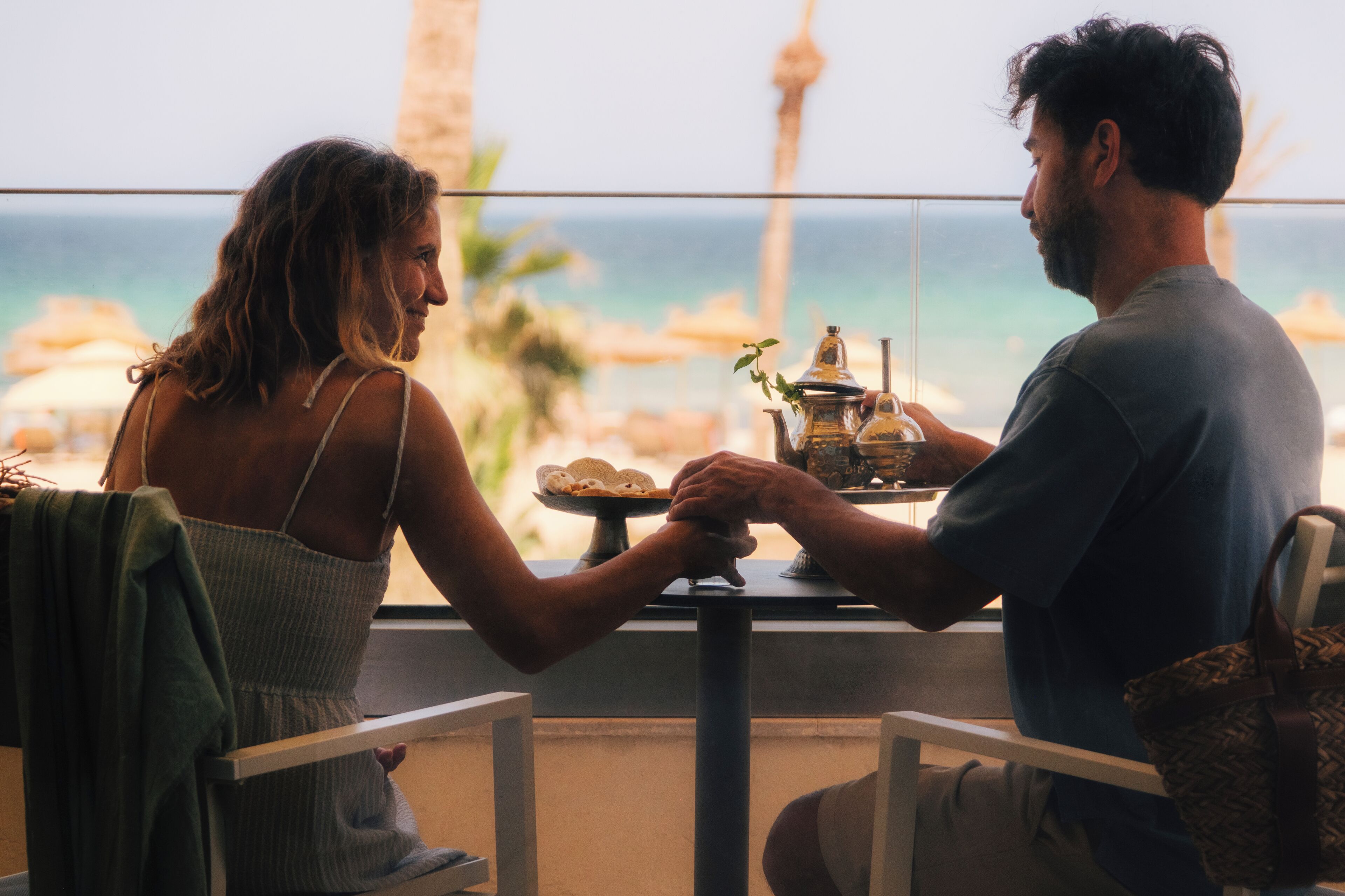 Un couple est assis à une table, devant laquelle s’étend une vue sur l’océan.