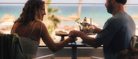 A couple dining at a table with a view of the ocean.