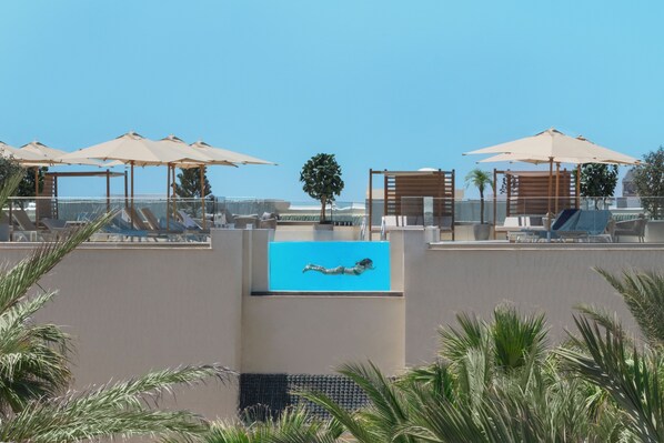 A rooftop pool area with lounge chairs and umbrellas, a clear blue sky, and a view of the ocean. - Iberostar Selection Eolia Djerba (Djerba Midun)