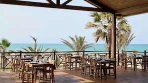 An outdoor dining area with wooden tables and chairs, overlooking the ocean. - Iberostar Selection Eolia Djerba (Djerba Midun)