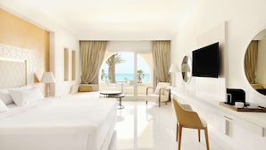 A hotel room with a large bed, a desk, a chair, a TV, and a view of the ocean. - Iberostar Selection Eolia Djerba (Djerba Midun)