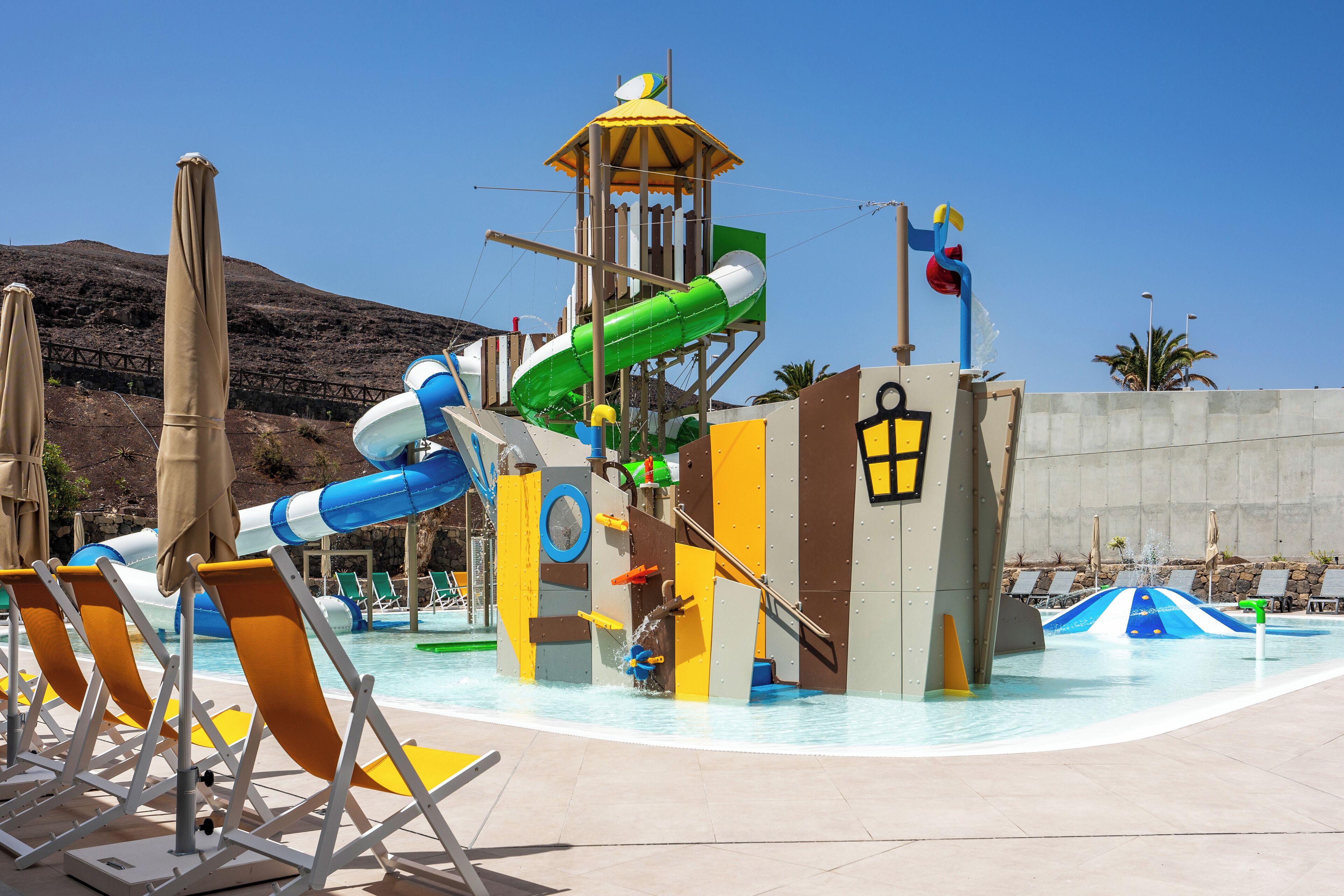 A water park with slides, a lifeguard tower, and lounge chairs.