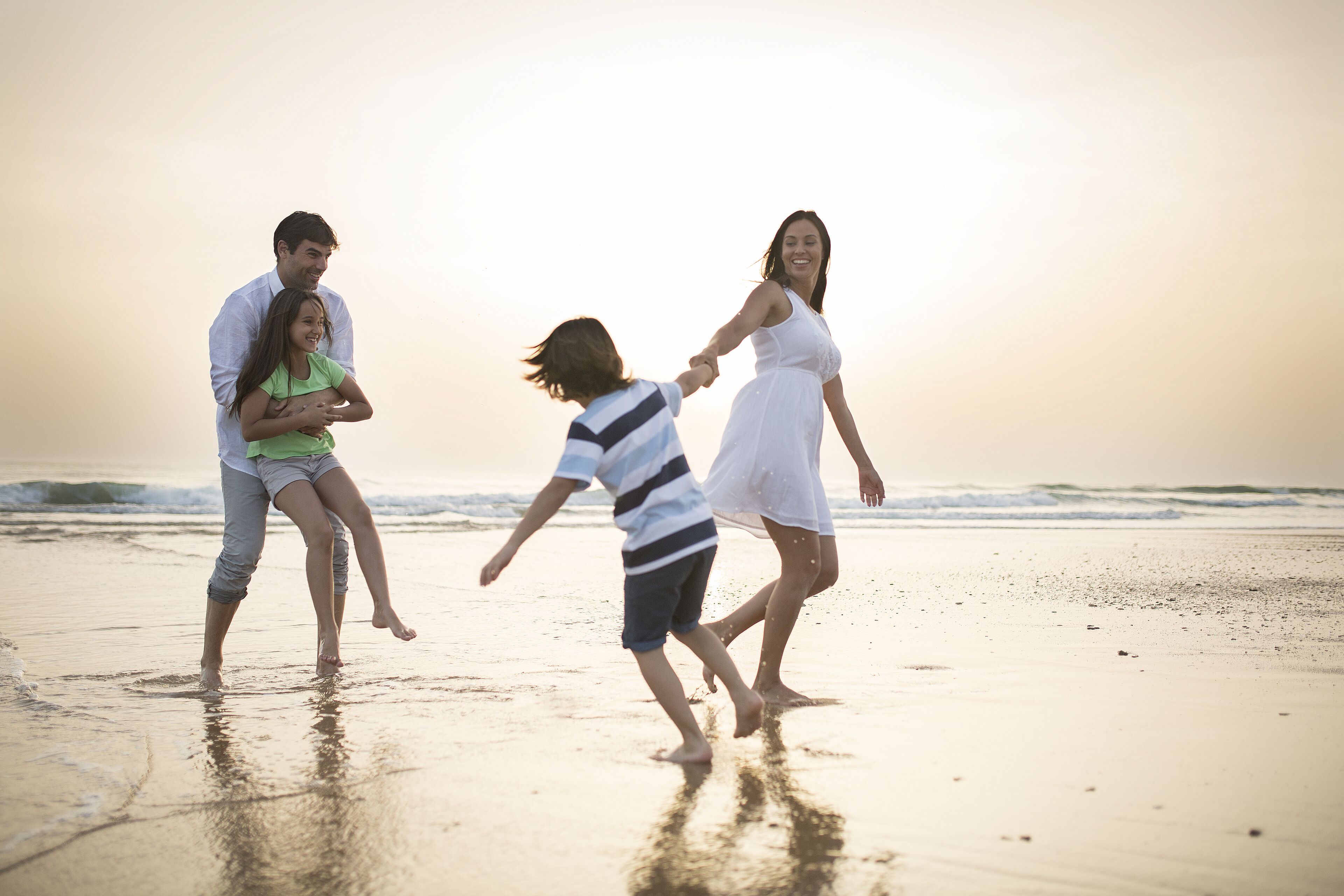A family walking on a beach with a sunset in the background.
