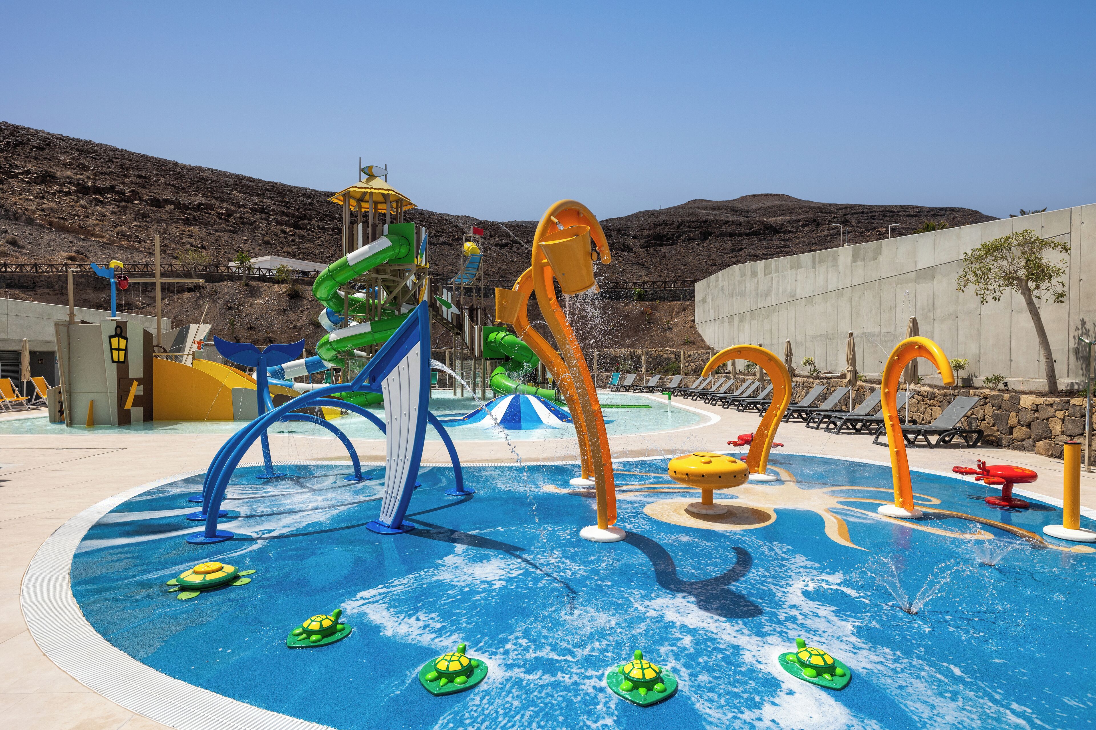 A water park with slides, a pool, and lounge chairs.