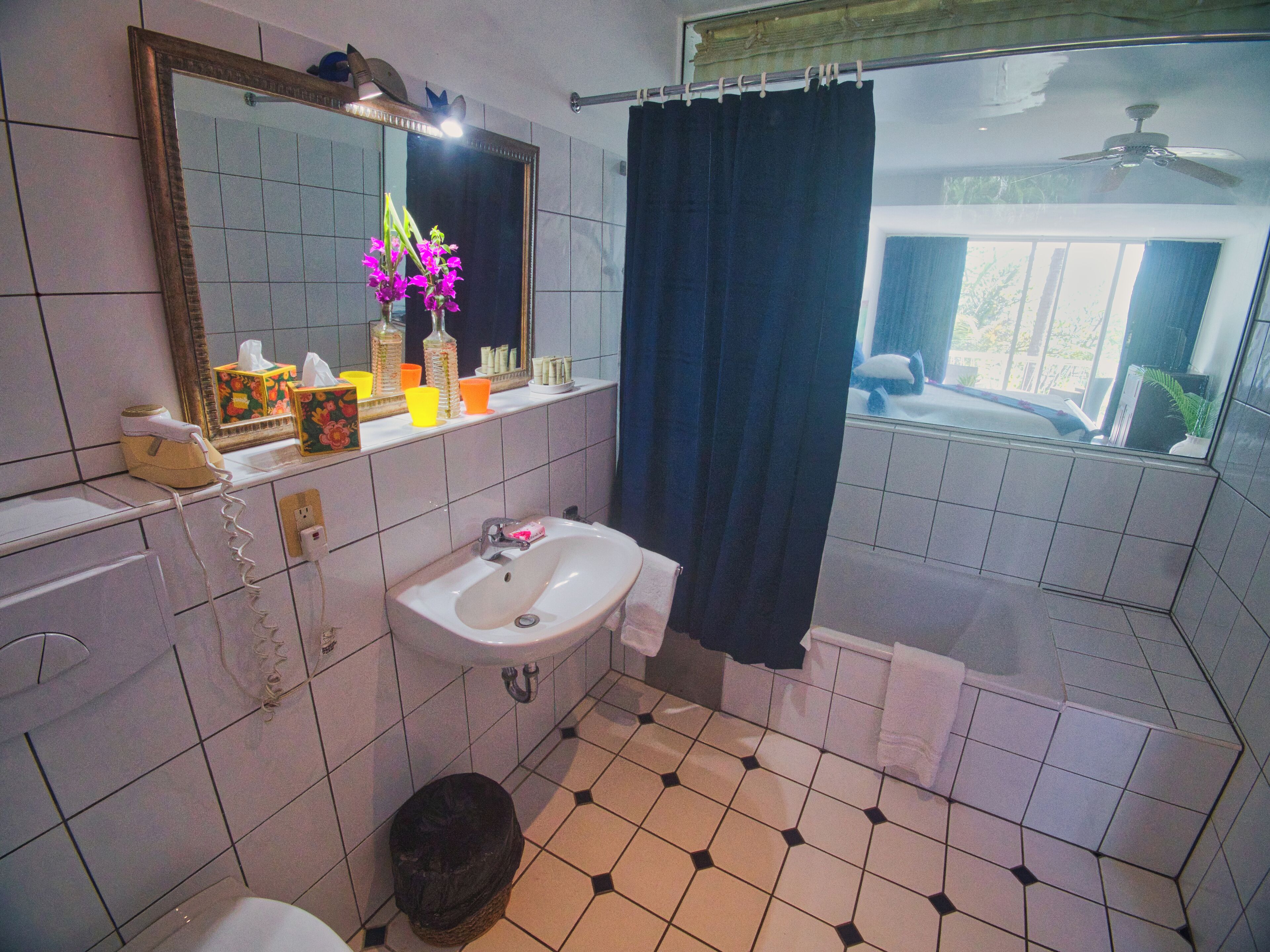 A bathroom with a sink, mirror, and toilet. There is a window with a view of the outside.
