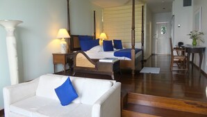 A hotel room with a four-poster bed, a white sofa with a blue pillow, a wooden desk, and a chair. - Blue Haven Hotel (Scarborough)