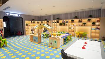 A children's play area with a blue polka dot floor, a small playhouse, and a foosball table.