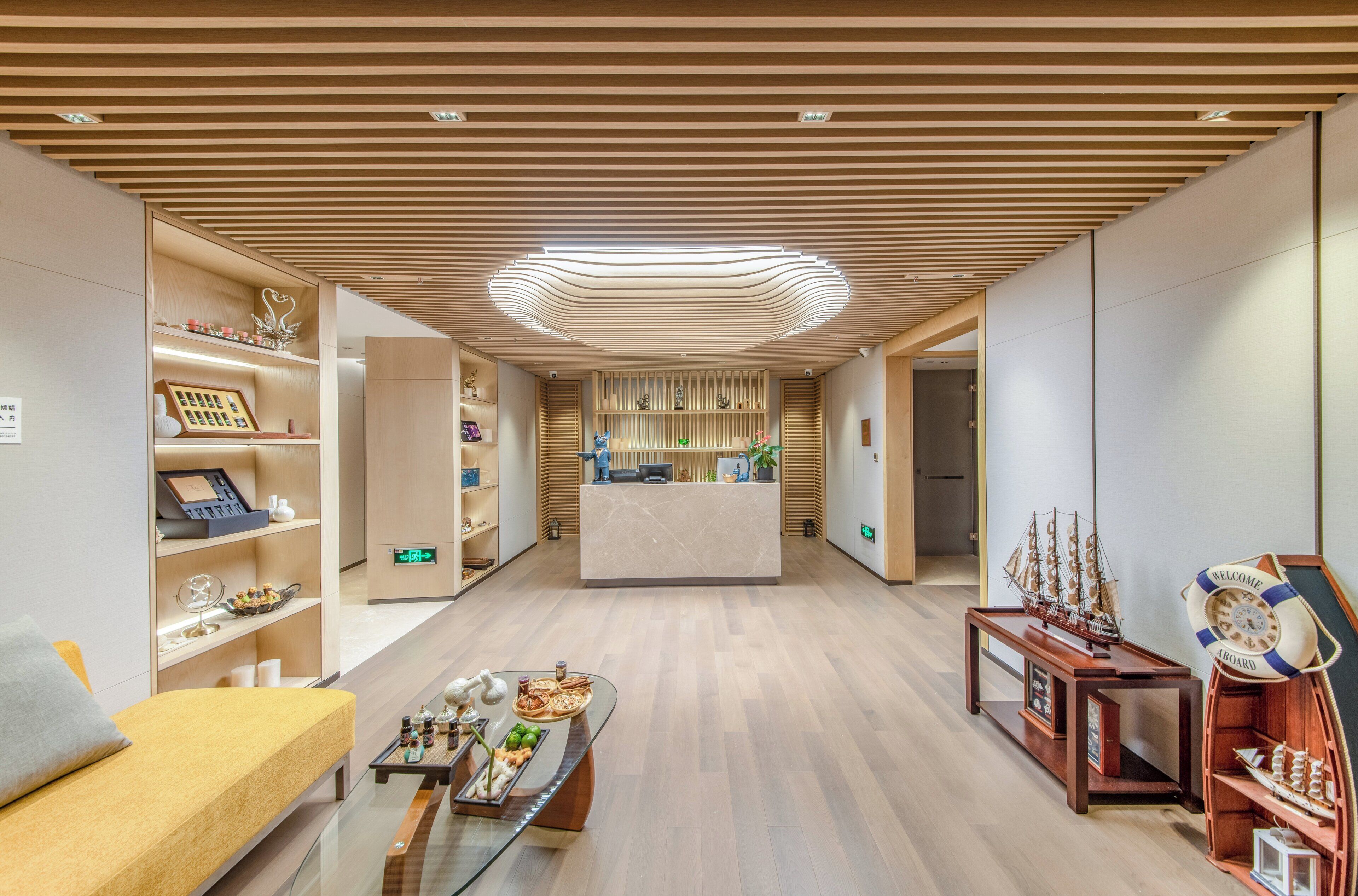 A hotel lobby with a reception desk, wooden paneling on the ceiling, and a reception area with a counter and chairs.