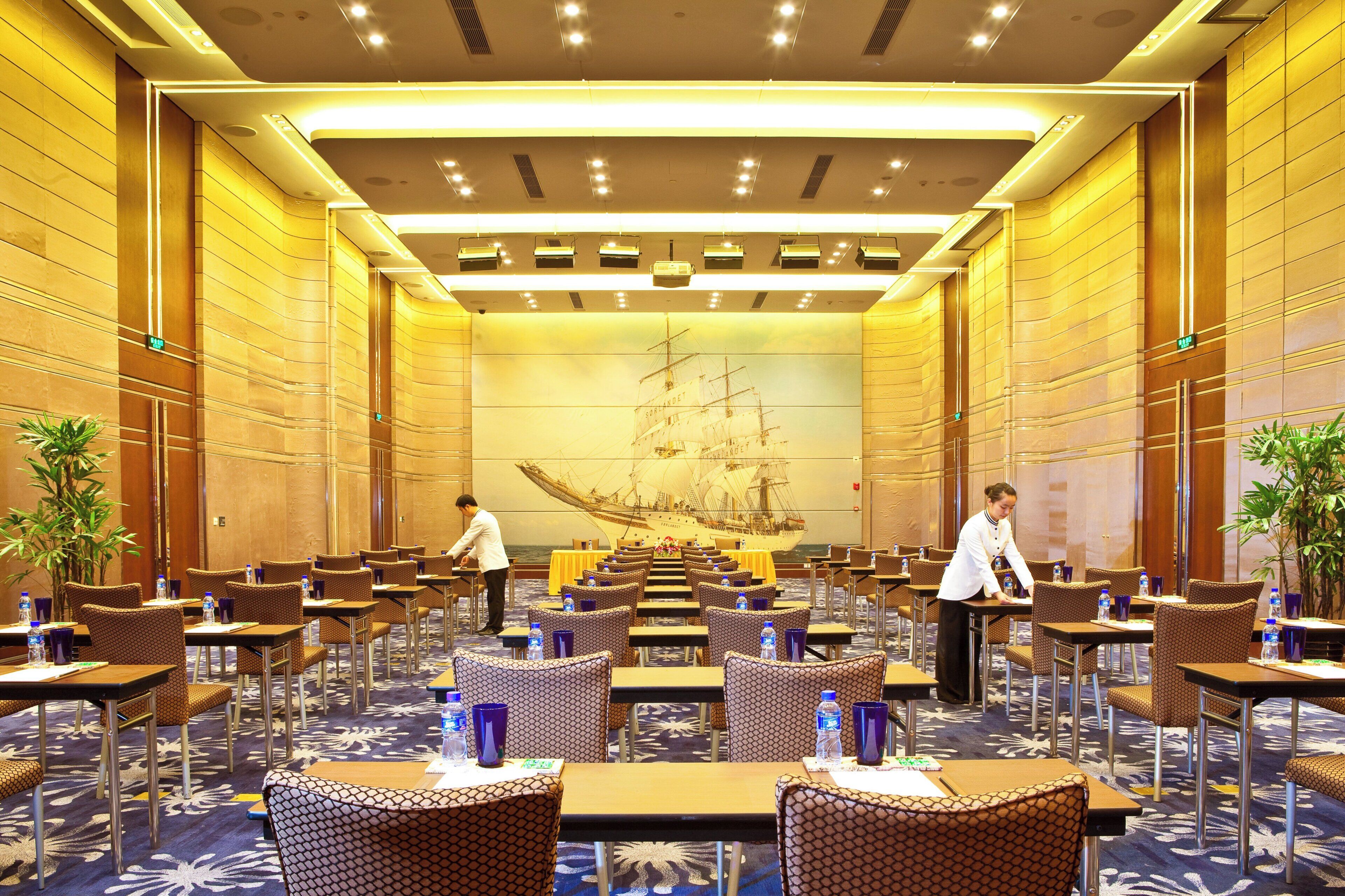 A hotel conference room with tables, chairs, and a large ship mural on the wall.