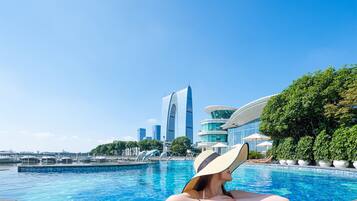 A woman relaxing by a swimming pool with a cityscape in the background.