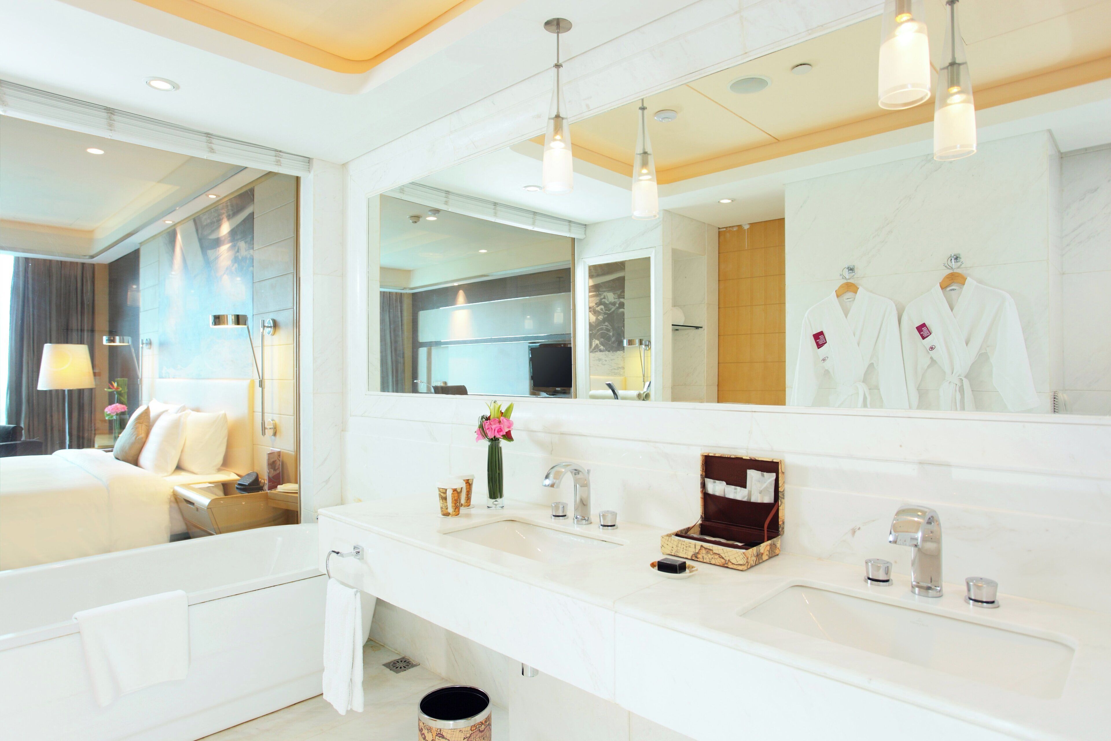 Un baño de hotel moderno con un espejo grande, una bañera, un lavabo y una ducha.