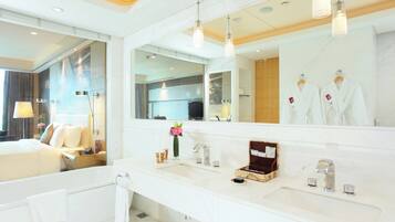 Un baño de hotel moderno con un espejo grande, una bañera, un lavabo y una ducha.