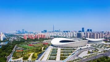 Uno stadio moderno con un tetto dalla forma originale, circondato da un parco curato e da un fiume.