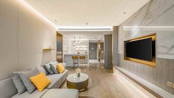 A modern living room with a sofa, coffee table, and a TV mounted on the wall.