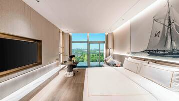 Una habitación de hotel moderna con una cama grande, un televisor de pantalla plana, una mesa de comedor y un ventanal con vistas a la ciudad.