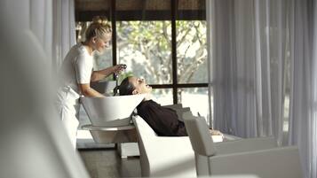 A modern room with a large window, a white chair, and a person attending to another seated individual.