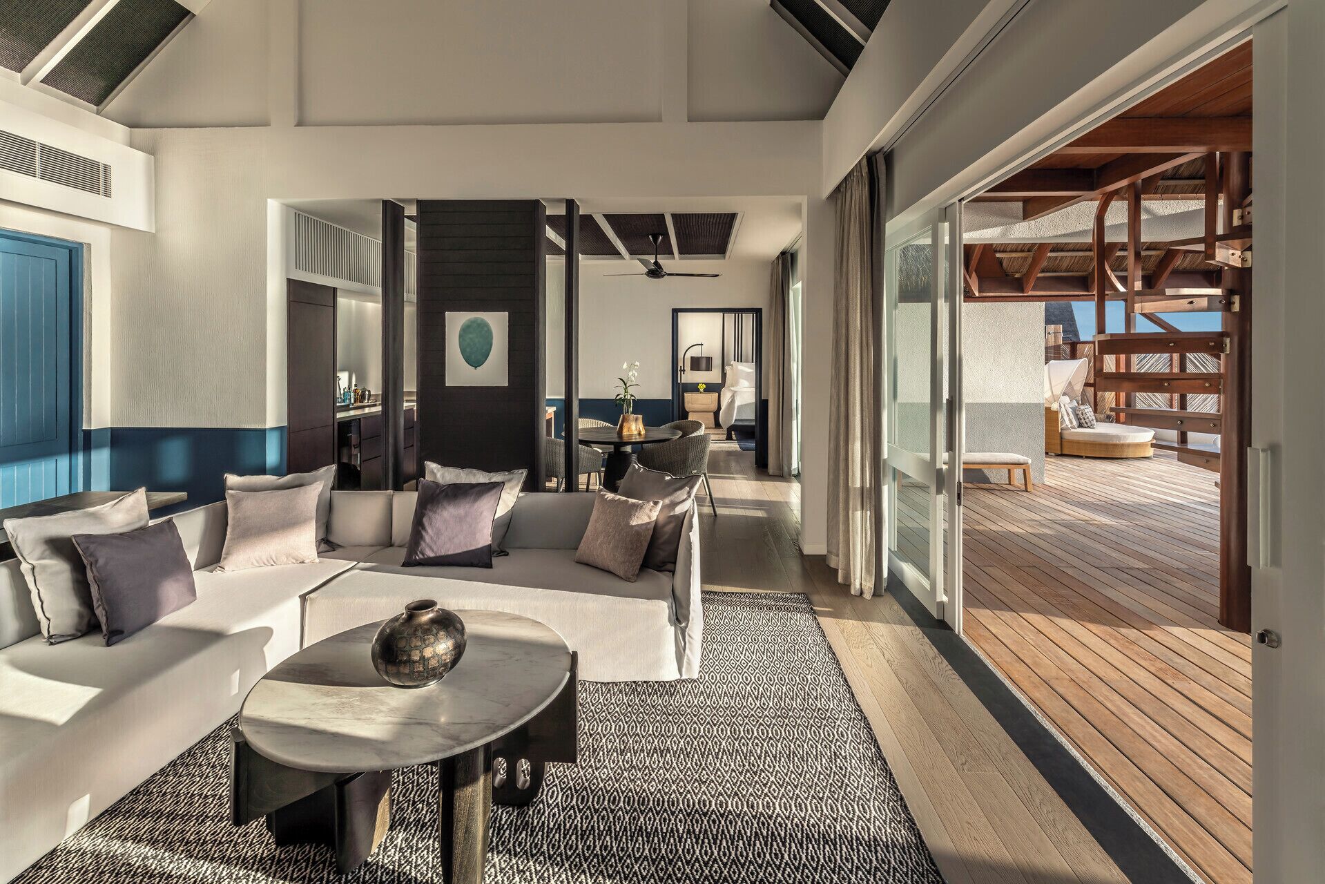 A modern interior with a sofa set, a round table, and a view of an outdoor deck.