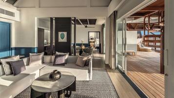 A modern interior with a sofa set, a round table, and a view of an outdoor deck.