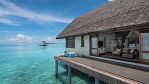An overwater bungalow with a thatched roof, wooden deck, and a view of the turquoise sea. - Four Seasons Maldives at Landaa Giraavaru (Landaa Giraavaru)