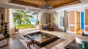 A spacious room with a large window overlooking a beach, a wooden ceiling, and a modern chandelier. - Four Seasons Maldives at Landaa Giraavaru (Landaa Giraavaru)