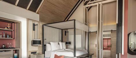A modern bedroom with a four-poster bed, bedside tables, a sofa, and a large mirror.