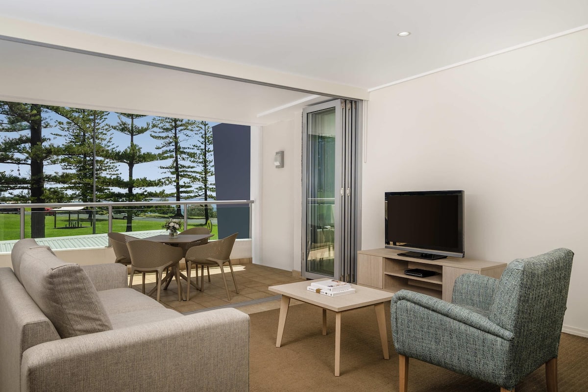 A modern living room with a sofa, a television, a small table, and a chair.