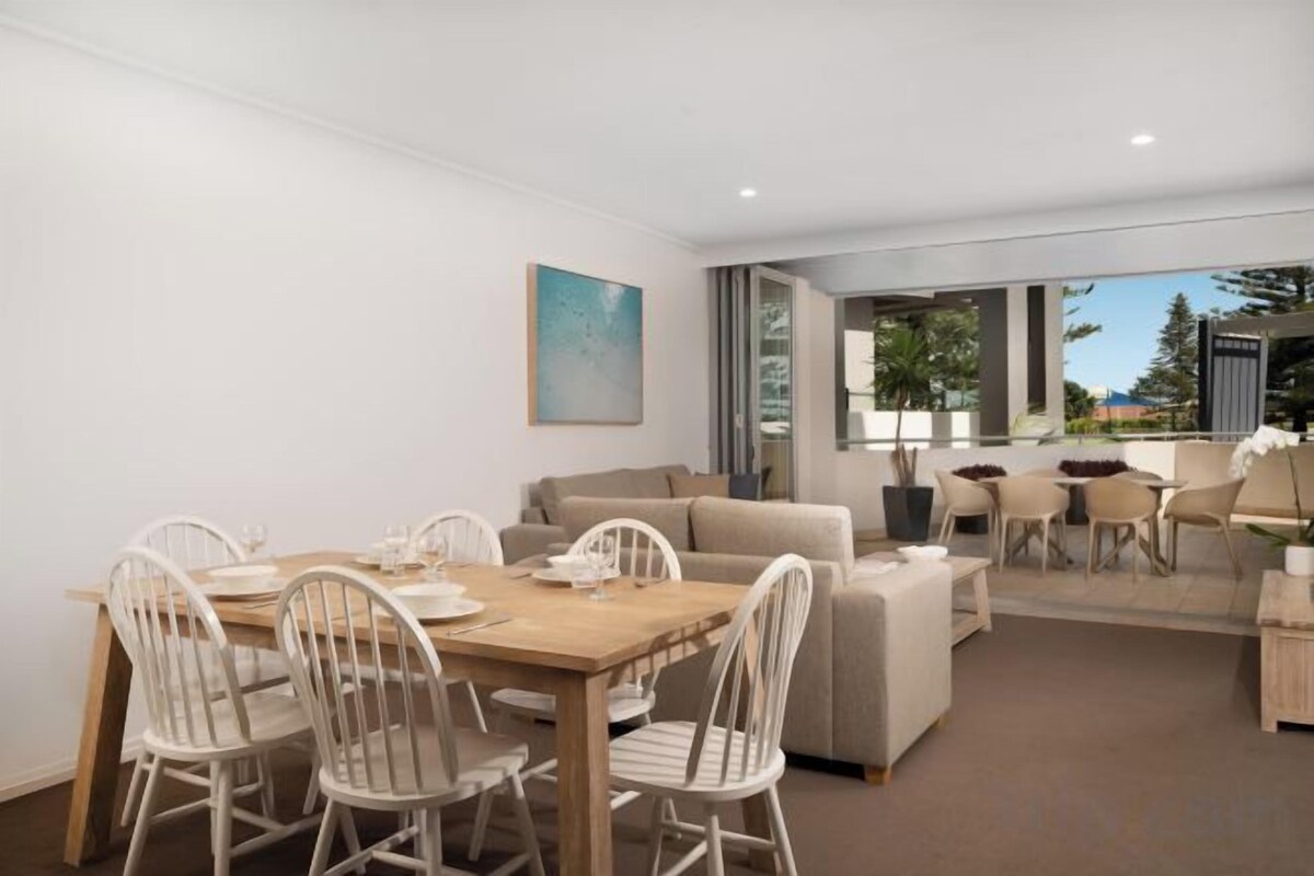 A modern living room with a dining area, a sofa set, and a view of the outdoors.