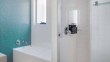 A modern bathroom with a bathtub, a glass shower enclosure, and a window.